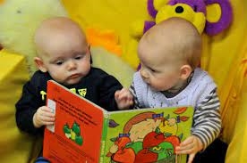 2 babies looking at book
