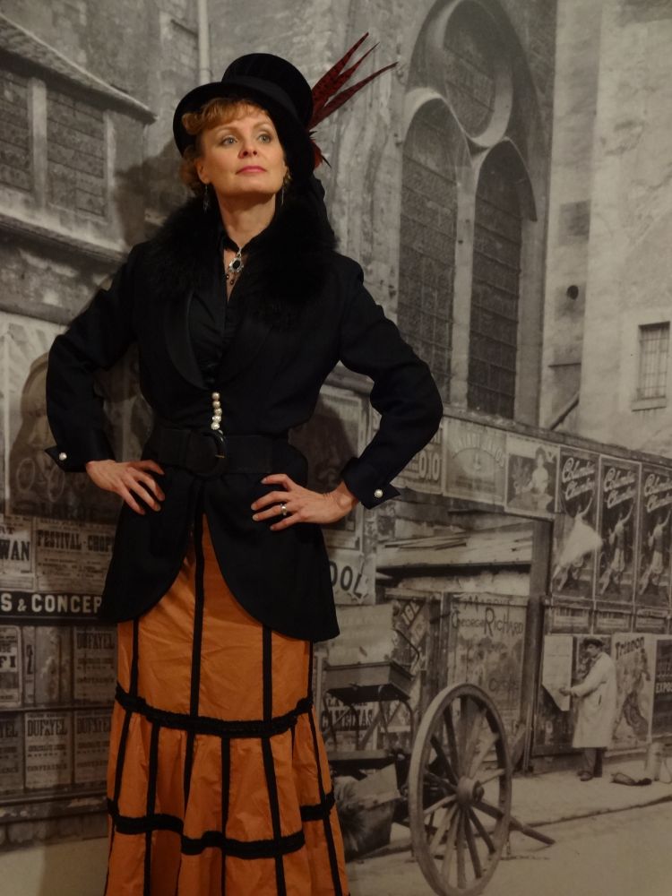 A female storyteller wearing a Dicken's inspired hat, coat and skirt.