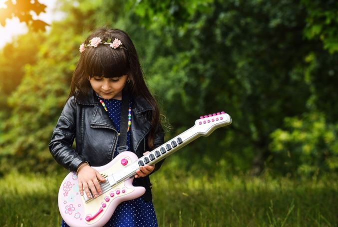 Young girl playing pink toy guitar