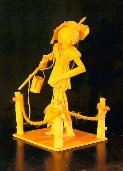 Corn husk doll standing holding bucket