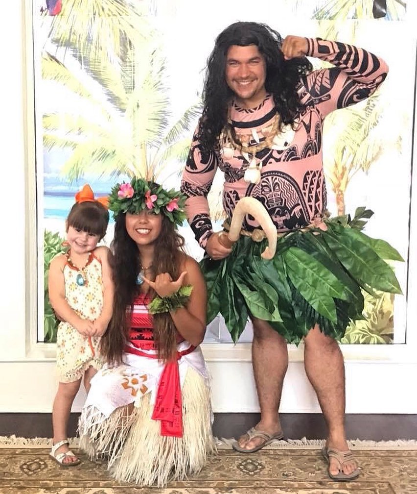 dancers dressed as Moana and Maui posing with child