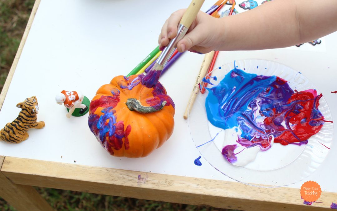 Child painting with bright fun colors on a small pumpkin