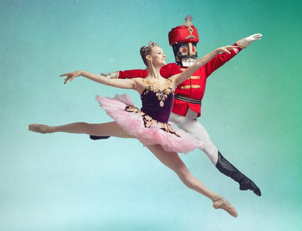 Ballet dancers leaping, one is dressed as a Nutcracker