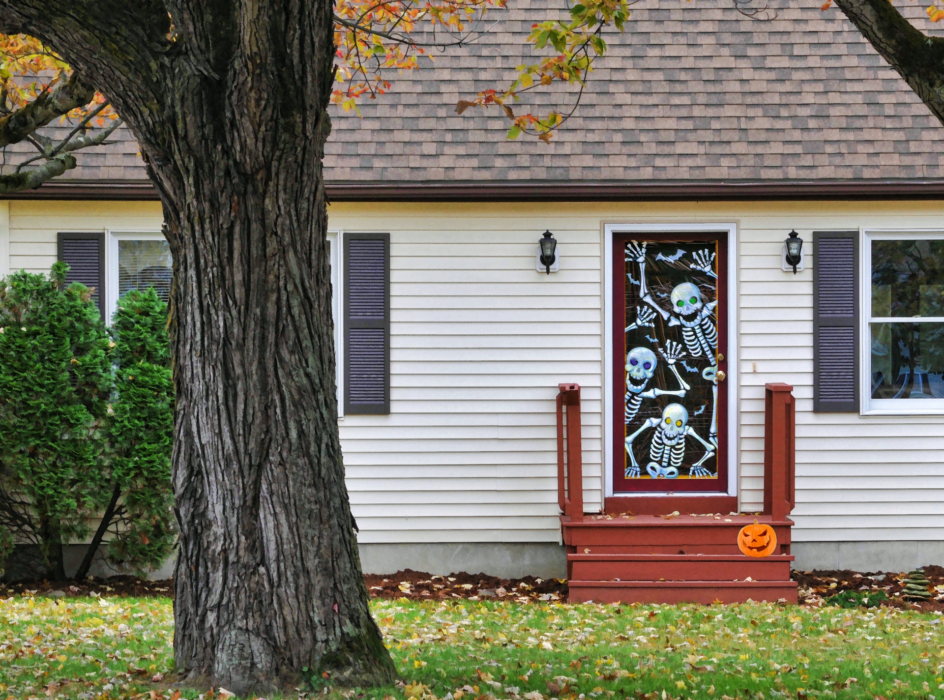 a porch with a skeleton door hanging and a pumpkin on of the steps