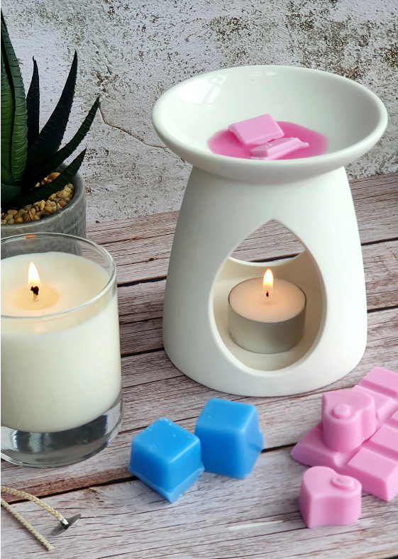 Wax melts and wax melter next to candle