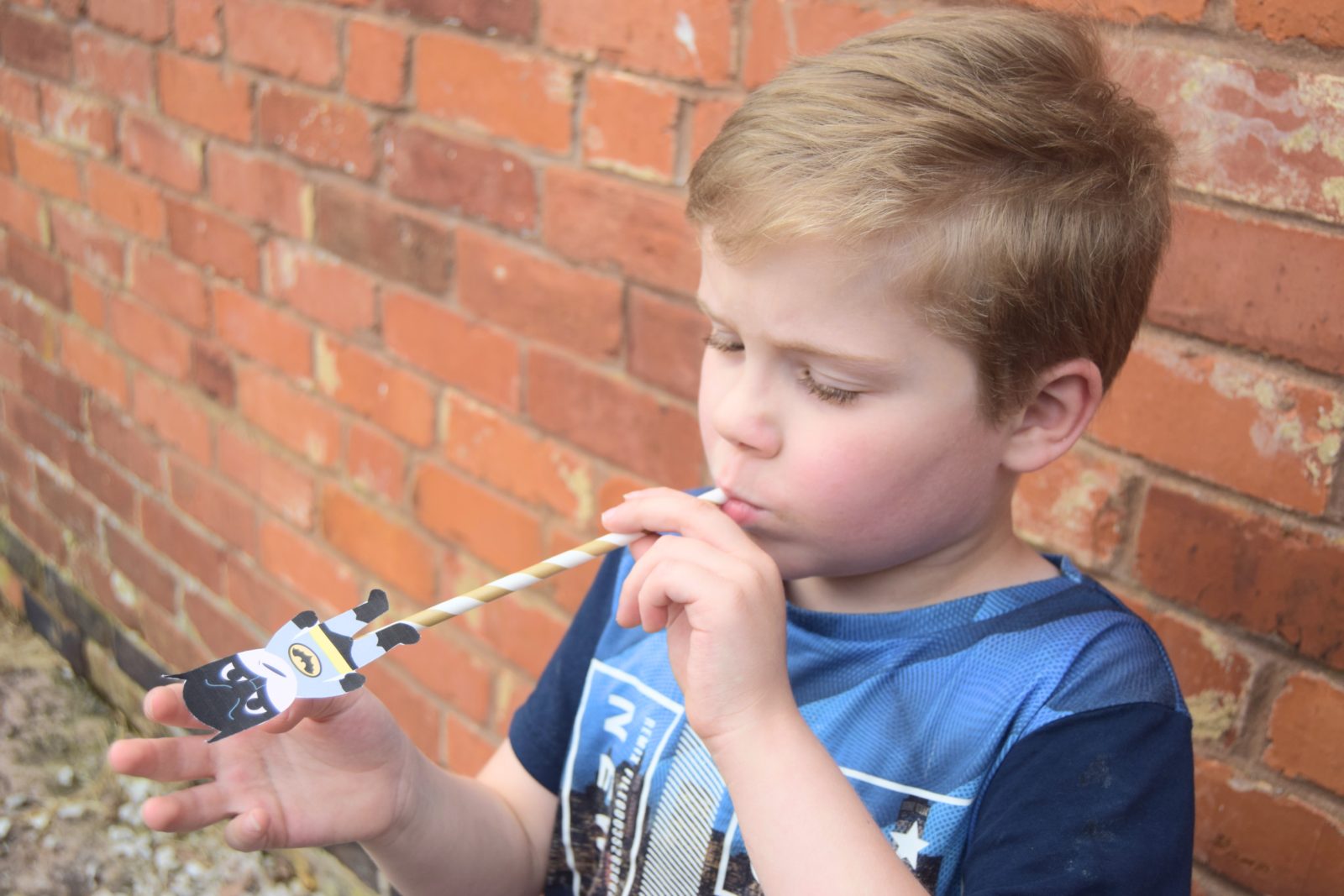 child holding a straw shooter