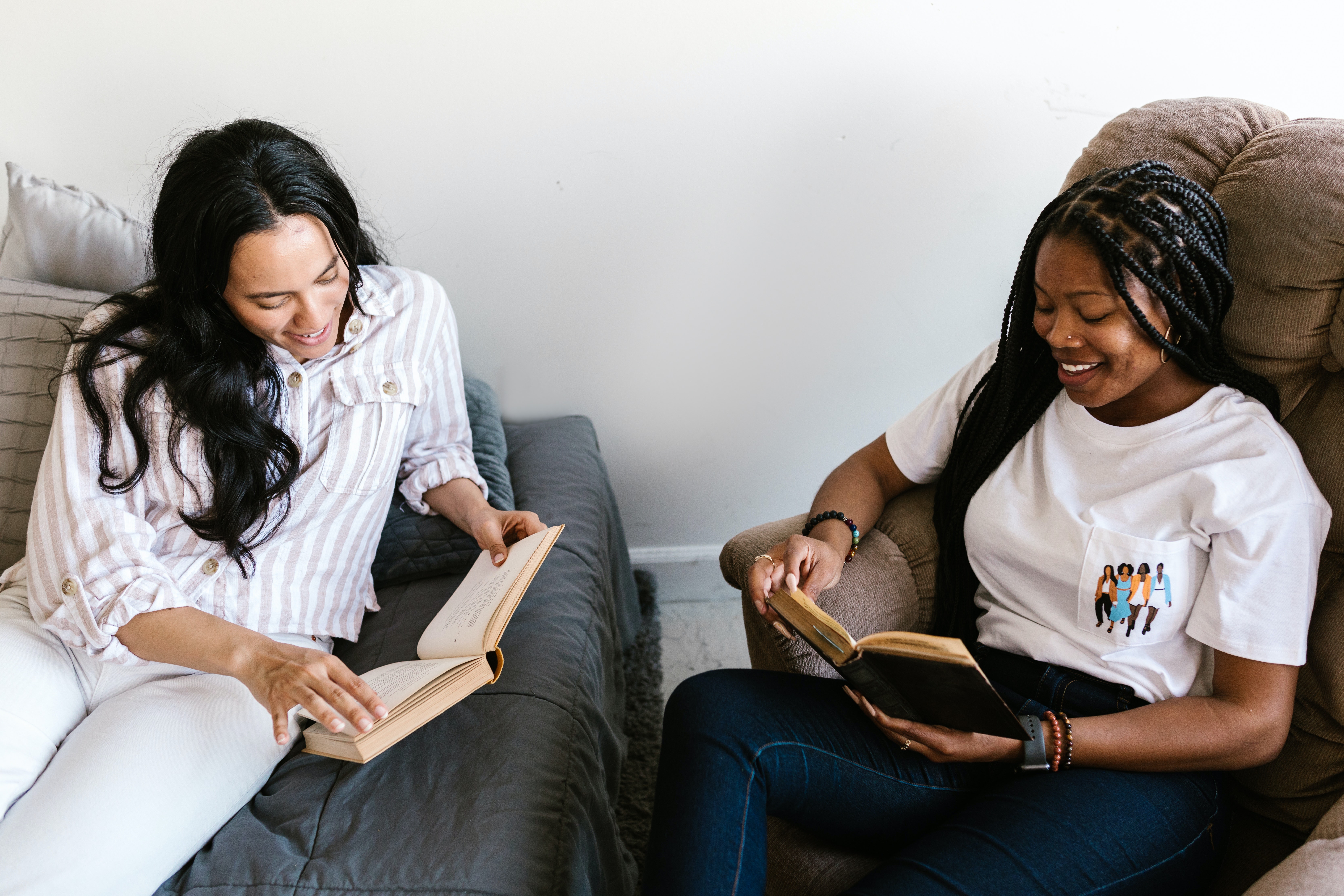 Two women sit together reading books.