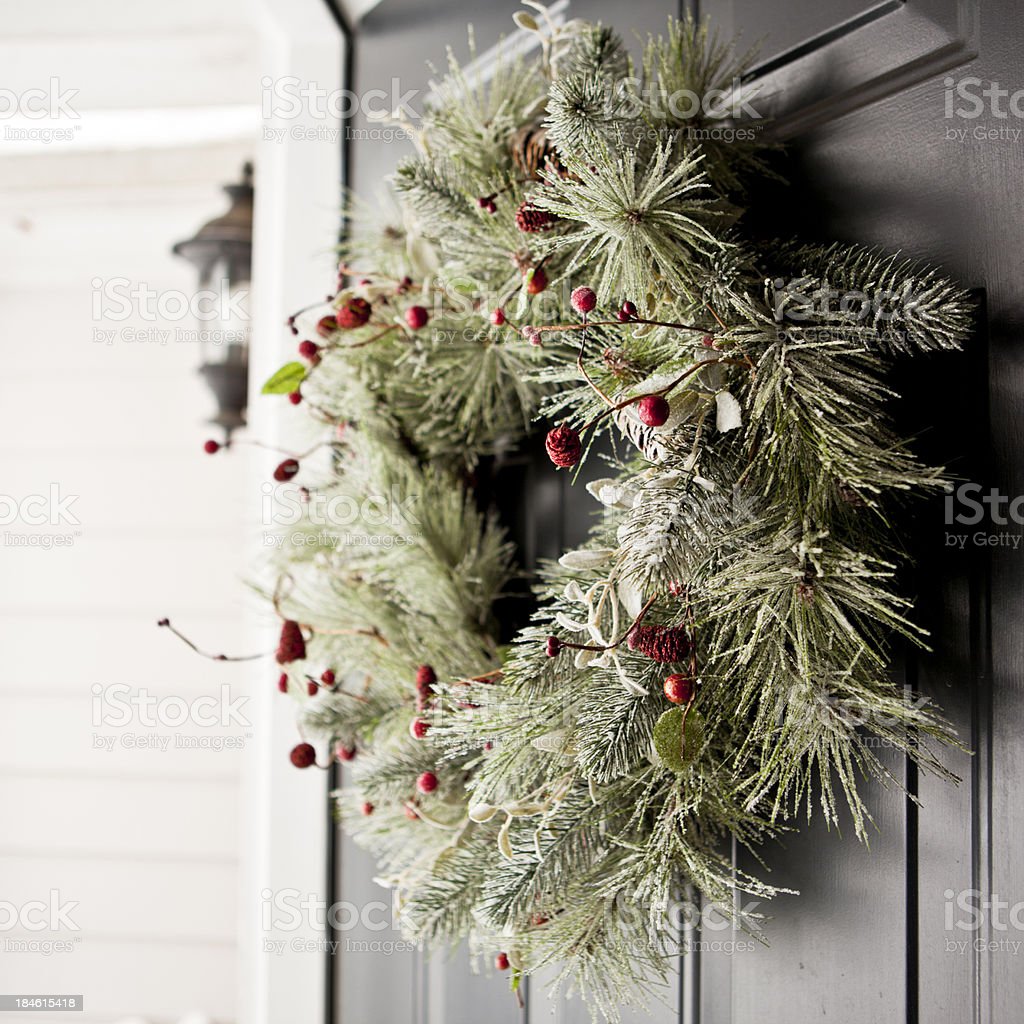 Wreath with Red Berries Hanging on Black Door