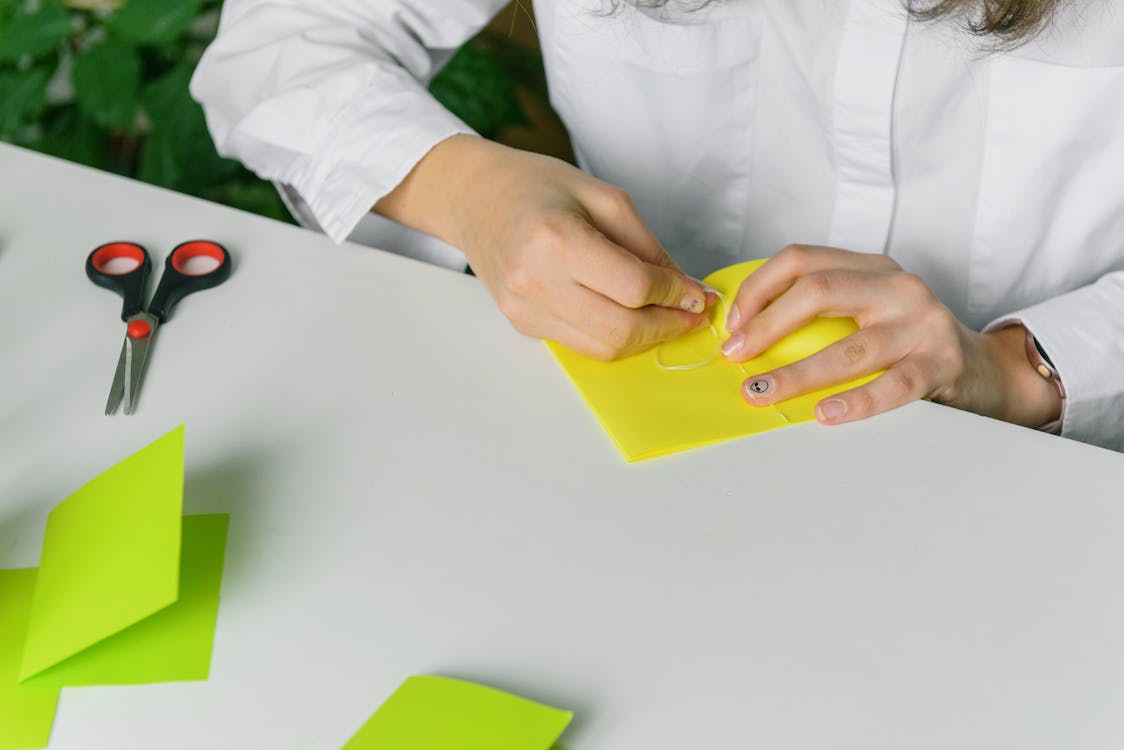 person folding colored paper on a table