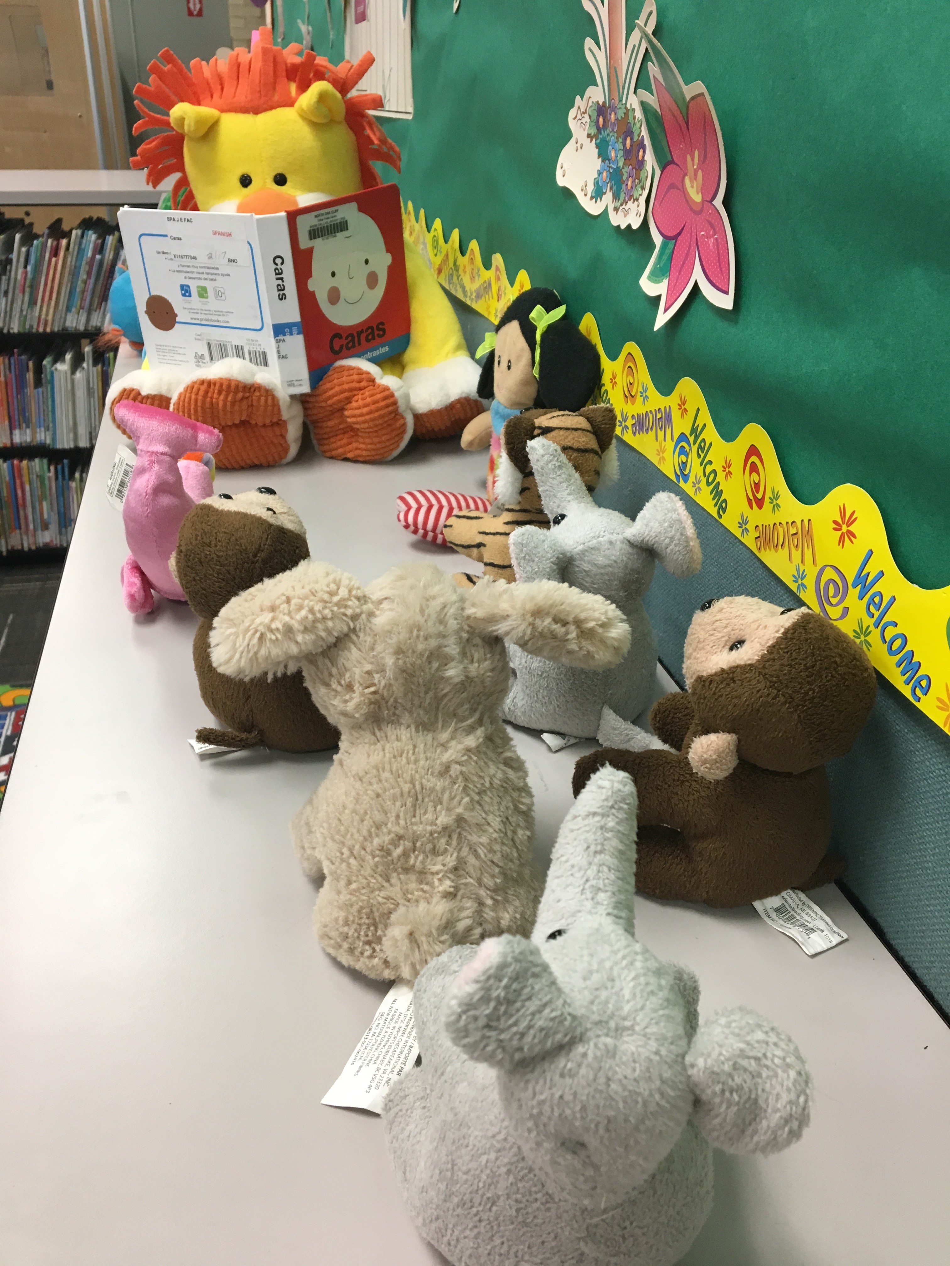 Row of stuffed animals sitting on top of bookshelves