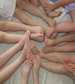 Happy bare children's feet and lower legs arranged in a circle.