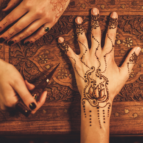 A hand being adorned with henna artwork.