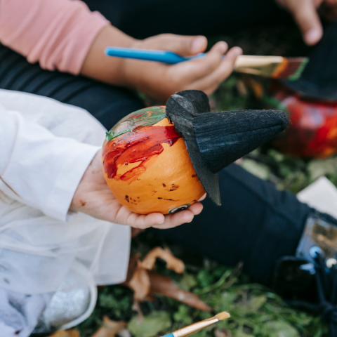 A child painting a tiny pumpkin.