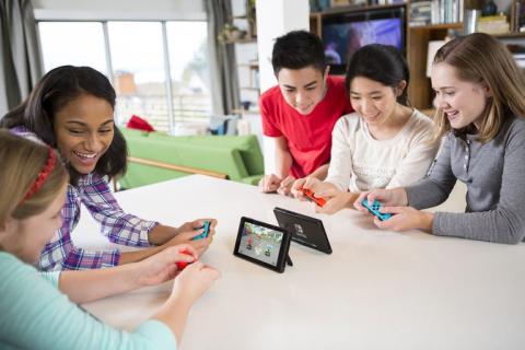 A group of five young people playing Nintendo switch console games.