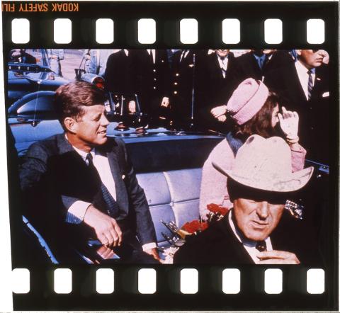 A 35mm color transparency film view of President John F. Kennedy and Jaqueline Kennedy seated in the backseat of the presidential limousine leaving Love Field Airport on November 22, 1963.