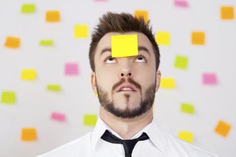man with yellow sticky note on his head, looking up