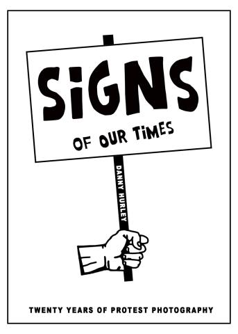 Hand holding sign that reads "Signs of Our Times"