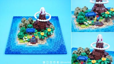 A LEGO island with a volcano from three points of view. The left half of the image is the entire island. The top right of the image is the base of the volcano. The bottom right of the image is a close up of the volcano. The island has a tall, brown volcano with a smoke ring around the top in the back left corner. The volcano is about one-fourth of the island. The other three-fourths of the island are taken up by various LEGO plant structures and a little house.