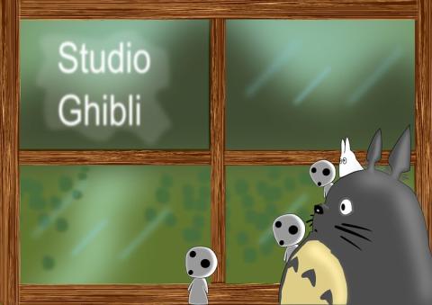 Totoro, with a small white Totoro riding on their shoulder, stand in front of a window with “Studio Ghibli” written in the upper left quadrant. The window has a green background and a wooden frame. Three Kodama are also with Totoro in front of the window.