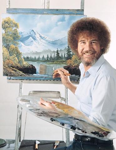 A smiling Bob Ross, paintbrush in hand, turned away from a painting on an easel. Photo credit: Jeff Nuveen, via Flikr 