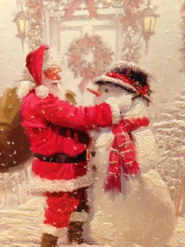 Santa is building a snowman. Santa is on the left of the image, and the snowman is on the right of the image. The snowman has a bowler hat and red scarf.