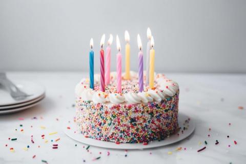 A white birthday cake with multicolored candles