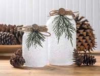 A photo of two frosted luminaries with pinecones in the background. 