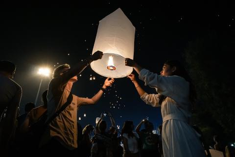 People releasing paper floating lanterns into the sky. 