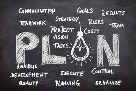 An image of a chalkboard with the word plan written in chunky text and the a in plan is replaced with a light bulb. Surrounding the Chunky word plan are different words one would use to describe goals and ways of achieving those goals such as, communications, goals, execute planning, etc. La imagen de una pizarra con la palabra plan escrita en texto grueso y la a en el plano se reemplaza por una bombilla. Alrededor del plan de palabras gruesas hay diferentes palabras que uno usaría para describir metas y fo