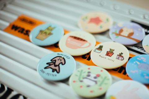 seven small pin-back buttons with cute designs. the one in focus says "qualified dog petter"