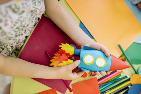 child holding a rocket crafted from paper