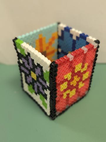 square cup made out of melted beads in floral patterns
