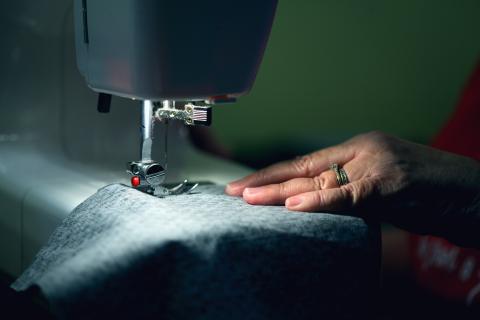 a hand holding fabric being sewed by sewing machine