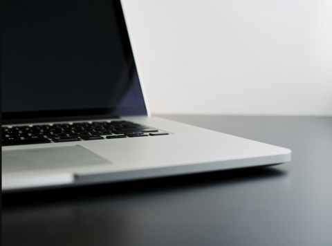 silver laptop computer sitting on a black desk