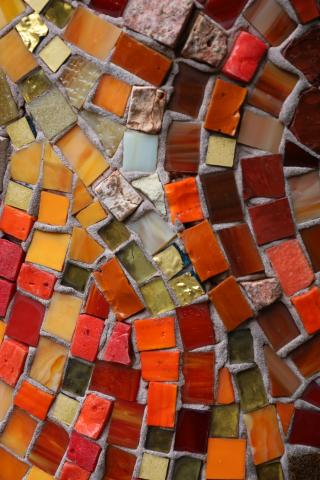 small square mosaic tiles in orange, brown, and yellow placed in curving lines