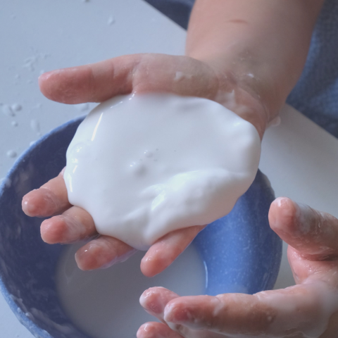 Child's hands holding a glob of white oobleck