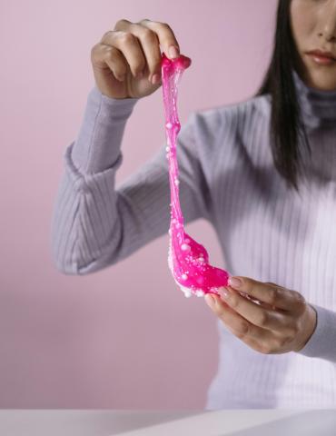 woman stretching pink slime between her hands