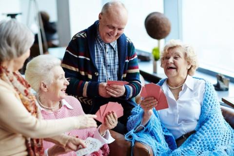 Four elderly friends smile as they play cards.