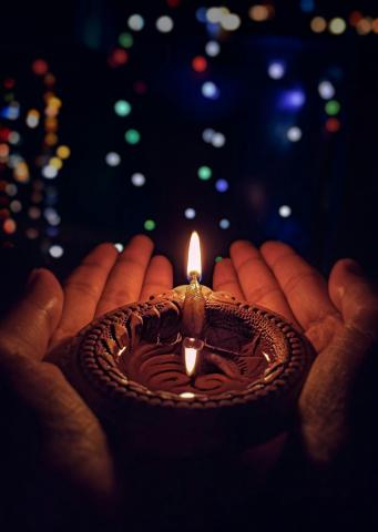 pair of hands holding a diya candle