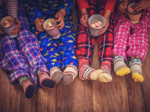 Four pair of children's legs in cozy pajamas and fuzzy socks 