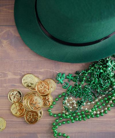 green top hat, gold coins, and green bead necklaces on a table