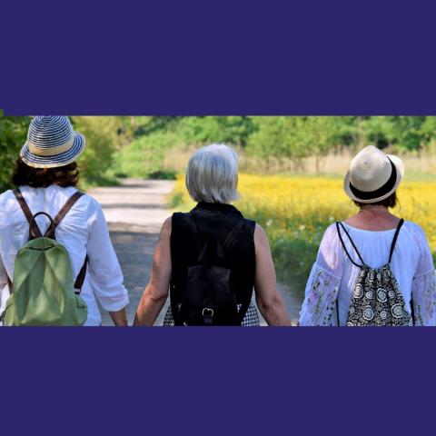 Picture of three women's backs. Women are of different generations and walking on a path