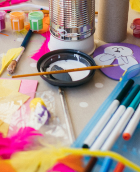 Various brightly colored craft supplies messily spread on table