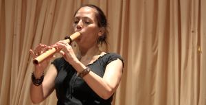 A woman playing a wooden wind instrument.