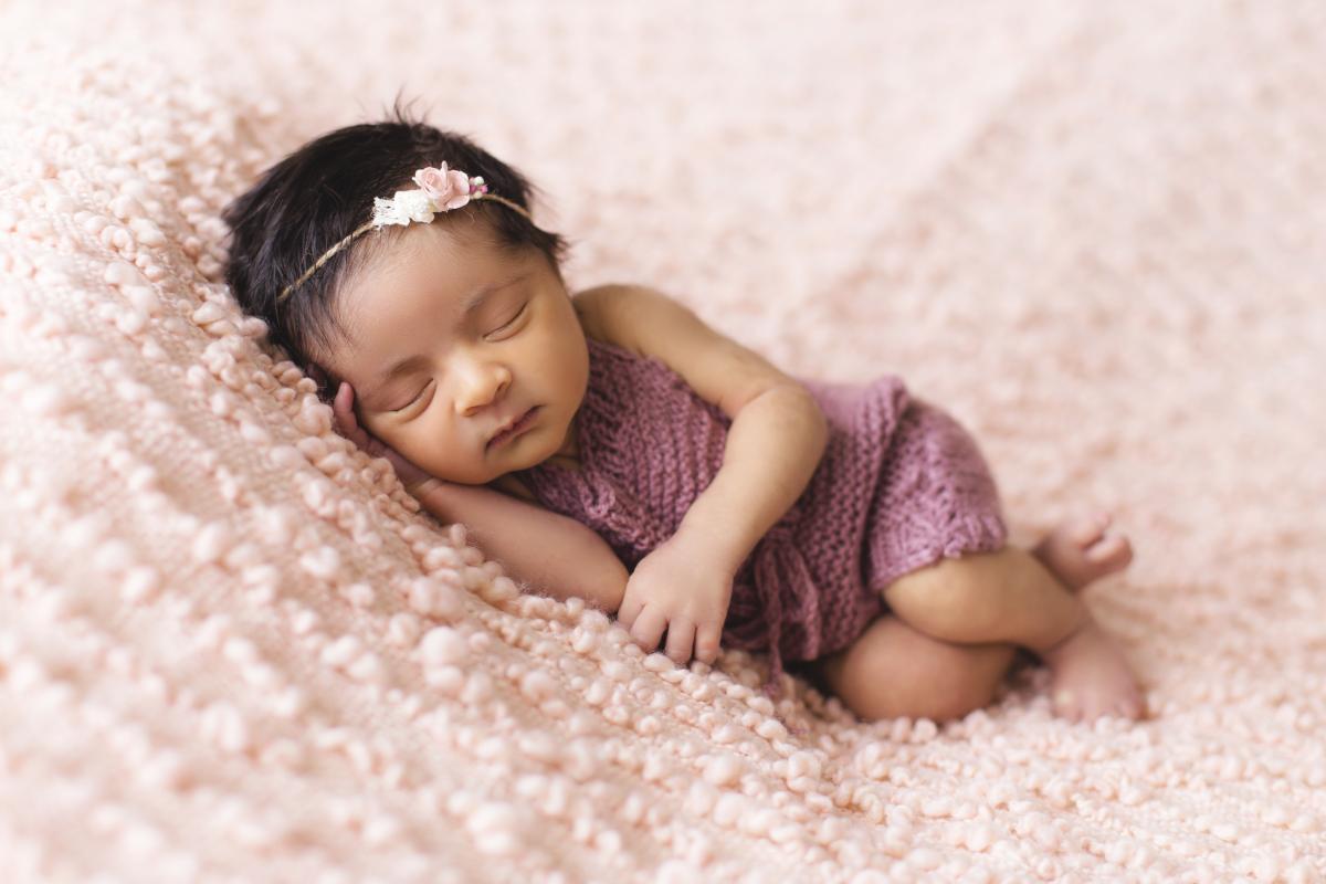 a small baby sleeping on a baby blanket.