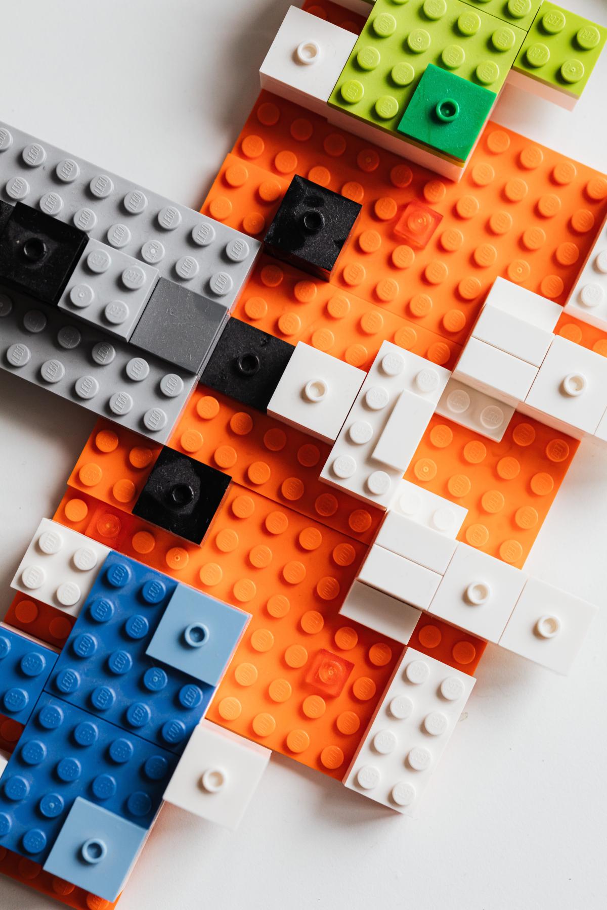 A Lego build consisting of an orange base with gray, white, green, and blue additions.