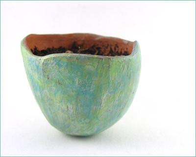 A small pinch pot that has been painted teal on the outside.
