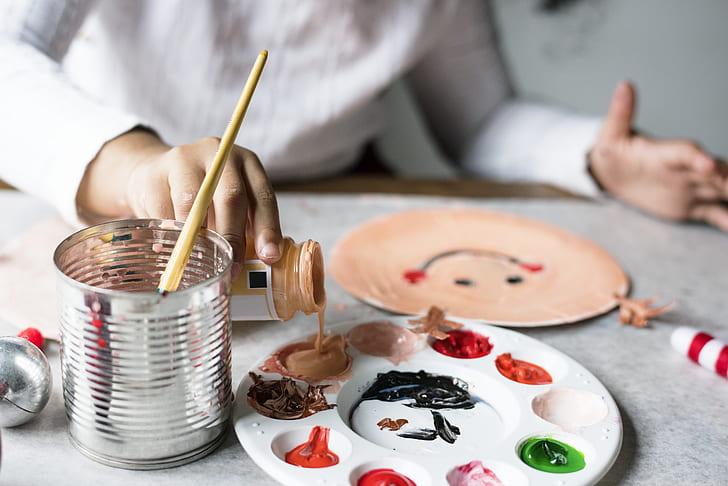 a child pours paint onto a palette 