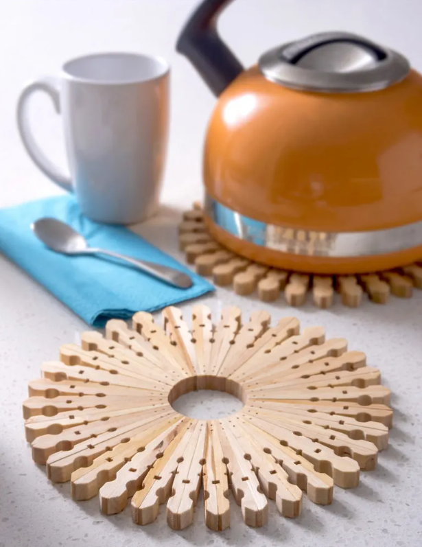 orange kettle with mug on top of trivet made of clothespins