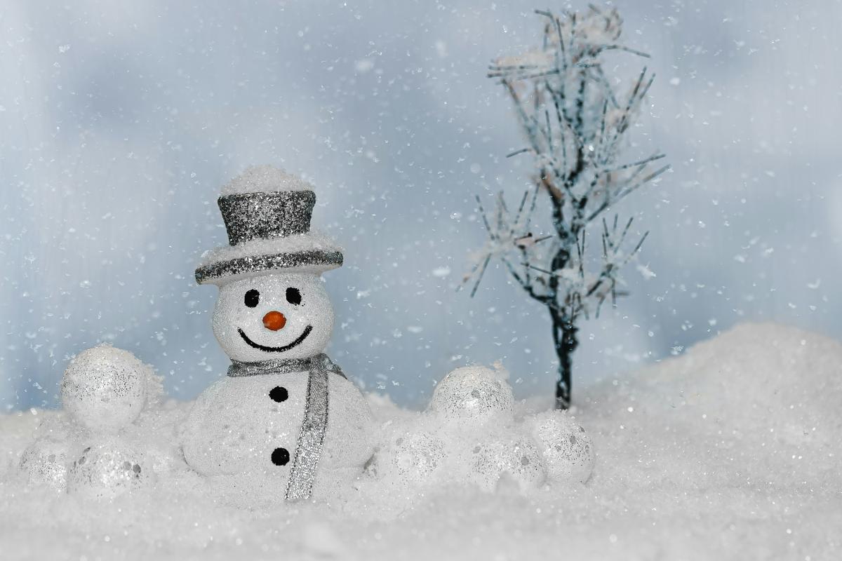 small snowman with top hat on fake snow with small tree